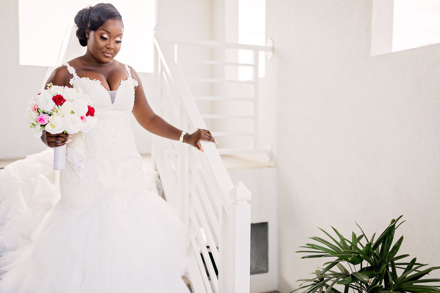 A bride in a flowing white gown twirls while holding a red and white bouquet.