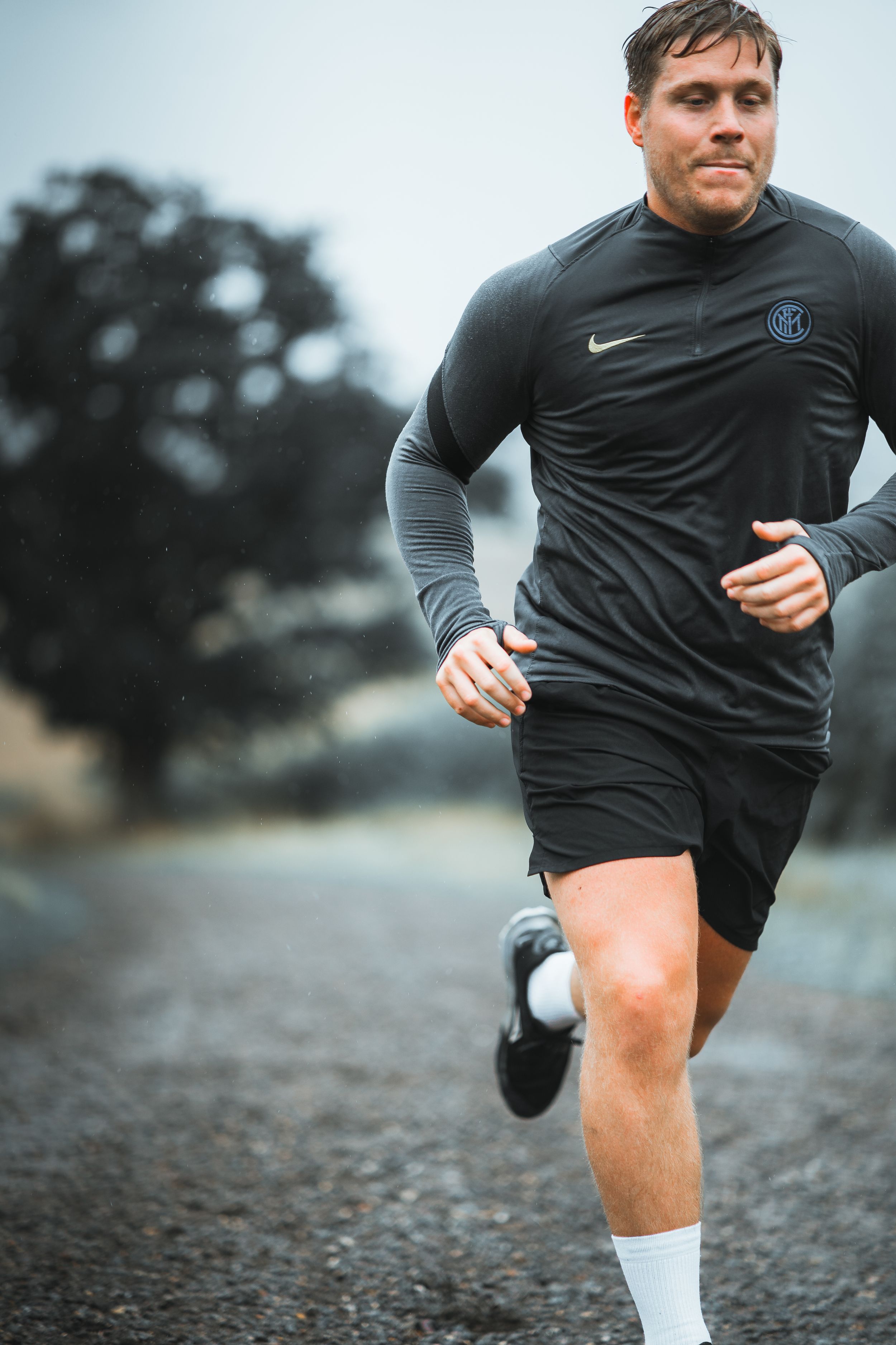 Athletic figure running on a trail wearing black Nike activewear and shorts.