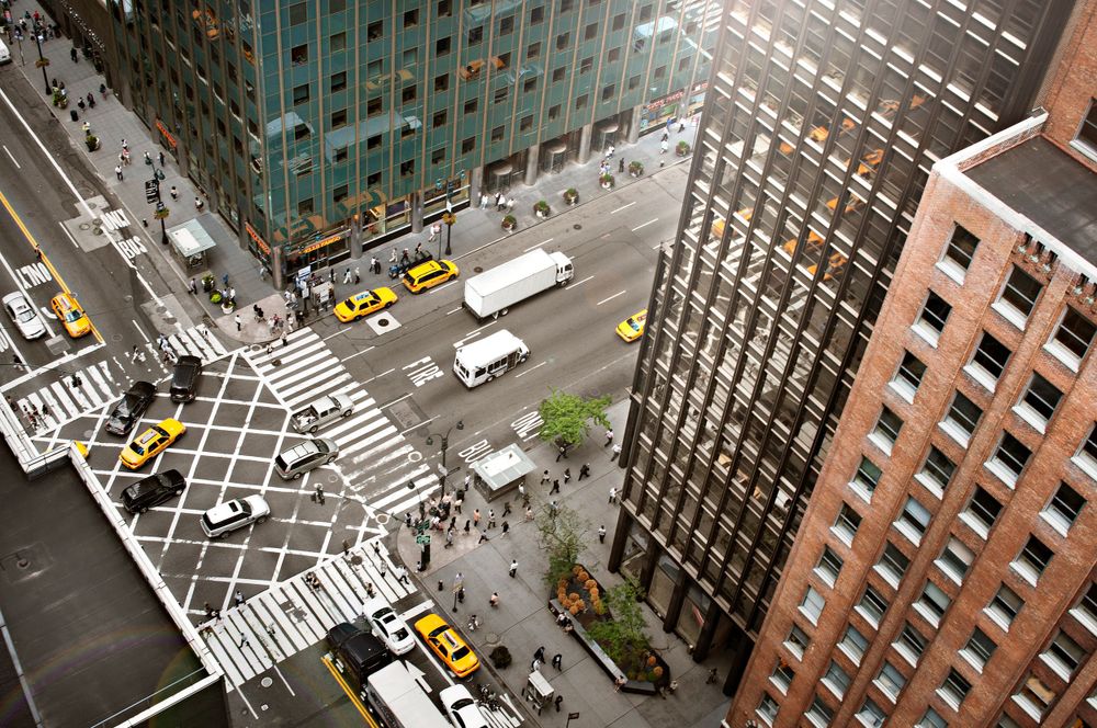 Aerial view of busy New York City intersection with yellow taxis and pedestrians crossing.