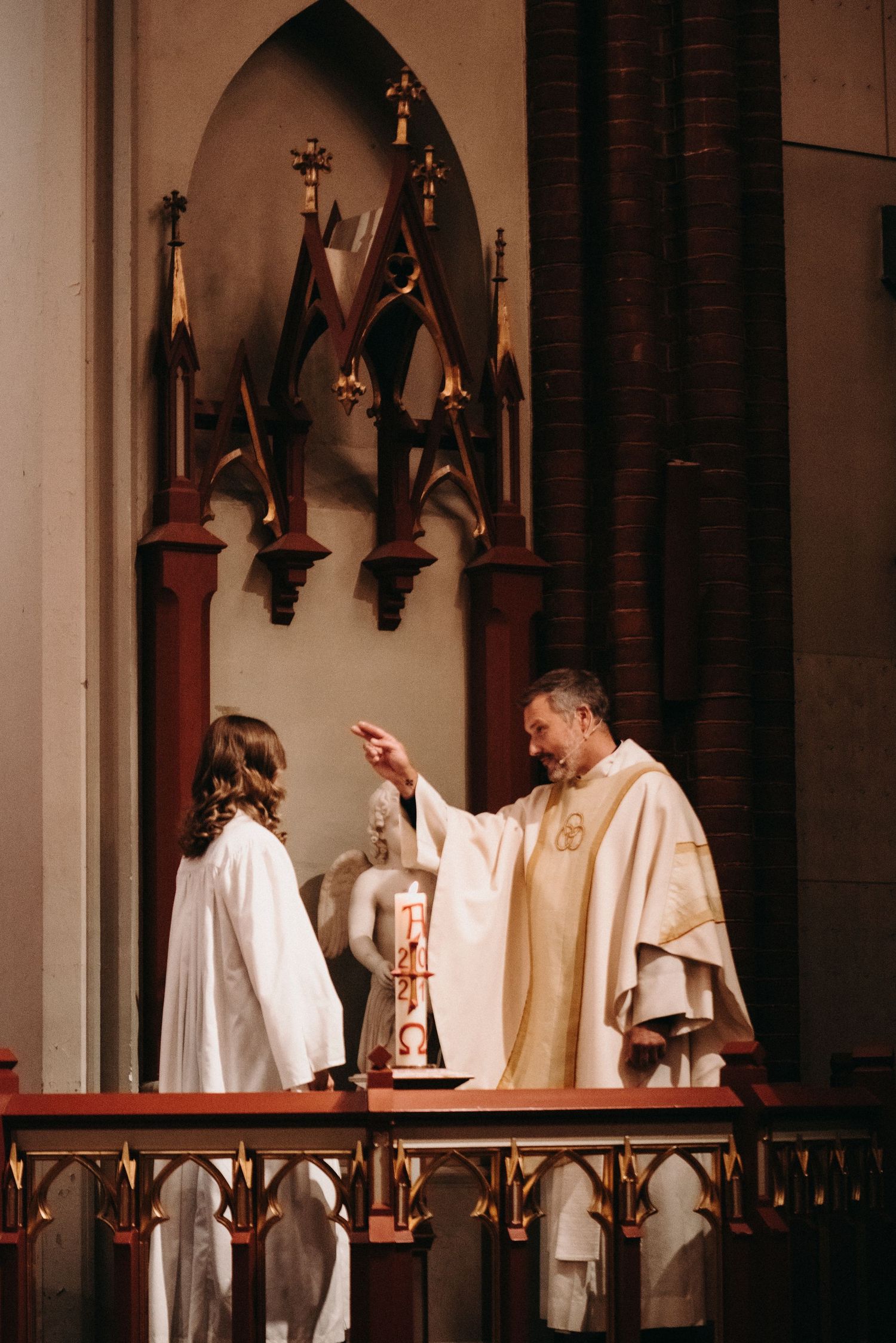 Religious blessing ceremony being performed at a Gothic church altar with decorative wooden details.
