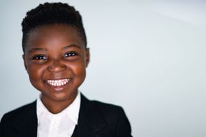 Professional headshot of a person in business attire with bright smile against light background.