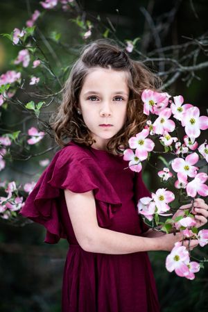 Portrait in burgundy dress among blooming pink dogwood flowers.