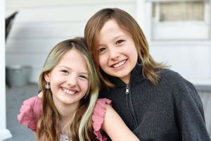 Two young friends smile warmly at camera wearing casual attire.