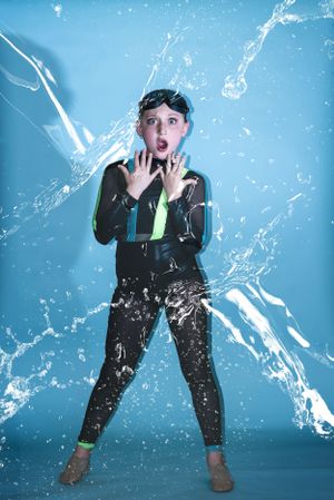 Dynamic water splash photography with figure in athletic wear against blue background.
