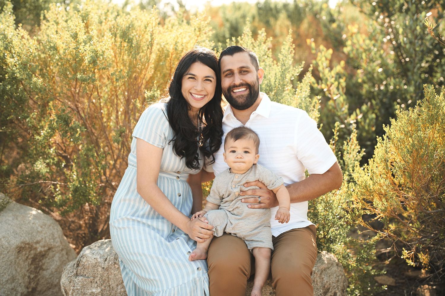 Family poses together on rocks during golden hour photoshoot.
