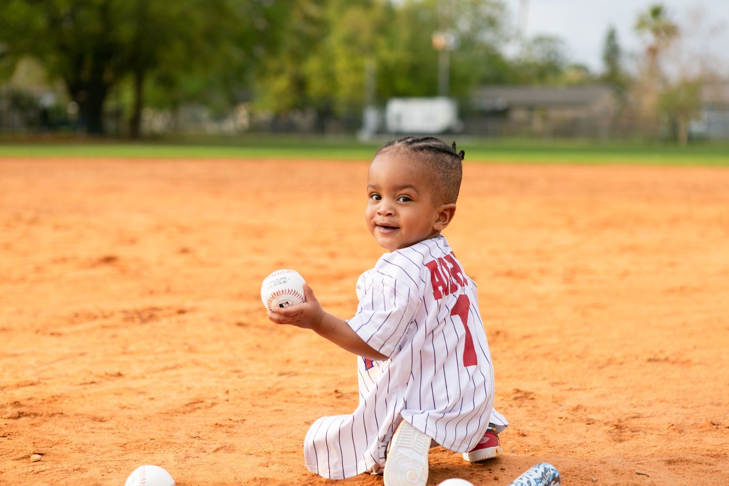 Sanford FL Cake Smash Photography boy holding a baseball on the baseball field