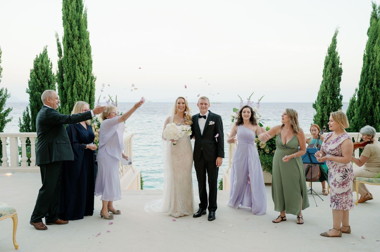 Wedding celebration on a mediterranean terrace with cypress trees and guests enjoying the moment.