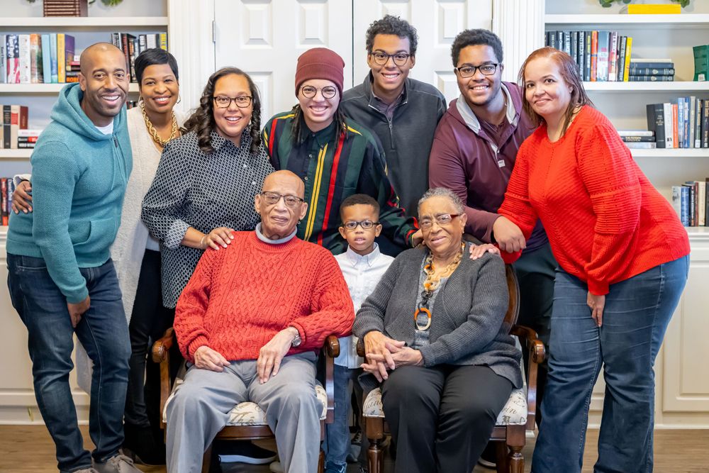 A group portrait of ten people gathered in a library setting with bookshelves behind them.