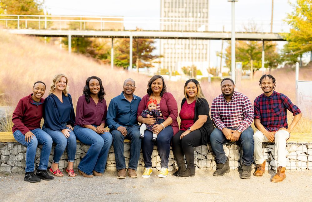 Group photo of family members wearing coordinated burgundy and blue outfits sitting together outdoors on stone steps.
