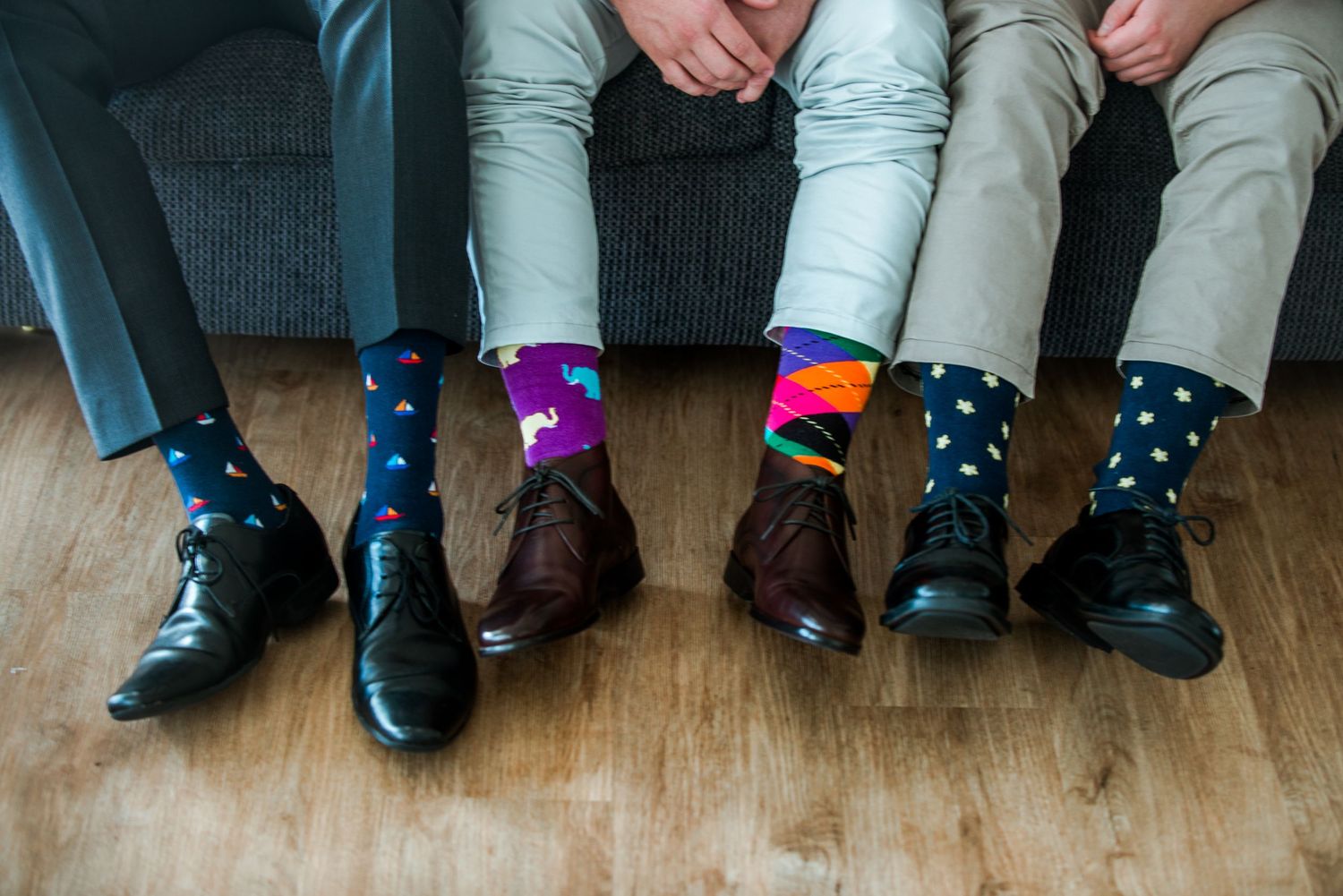 Guests showing off their colorful patterned socks with dress shoes on wooden floor.