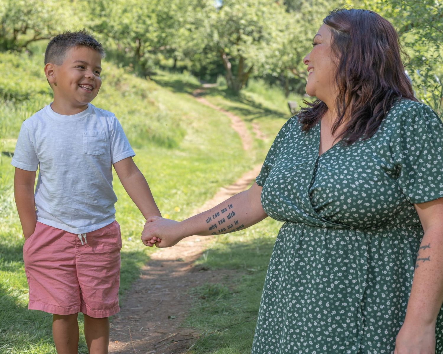 Woman and young boy hold hands and share a smile.