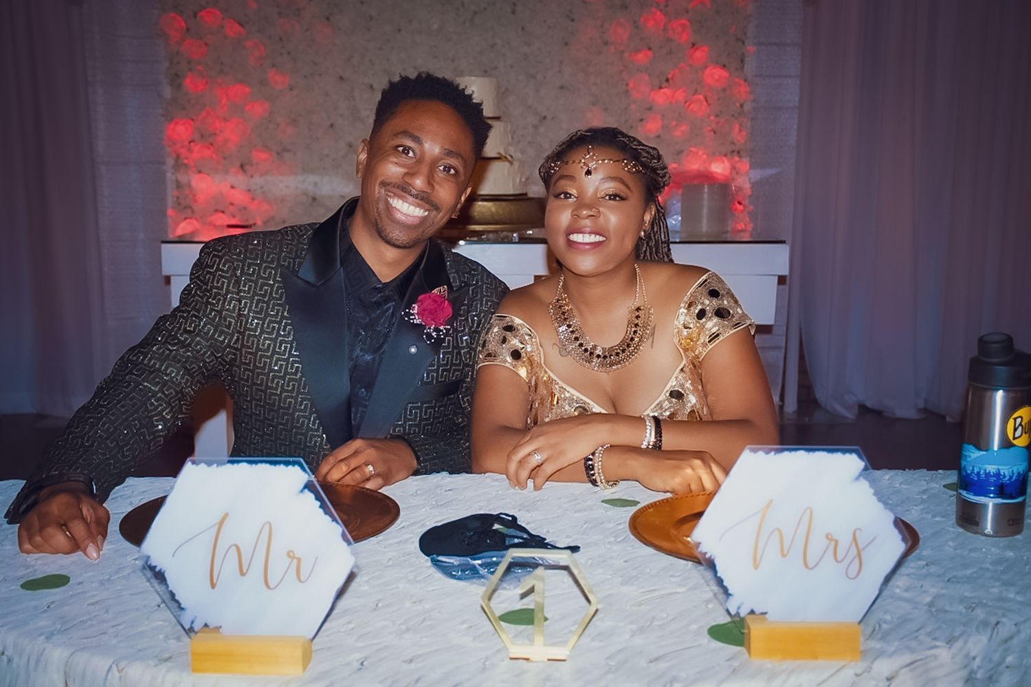 Couple signing marriage documents at a table with red lighting and decorative details.