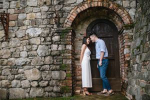 A couple sharing an intimate moment in a stone archway doorframe.