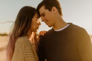 Romantic sunset portrait of couple in warm light and casual sweaters.