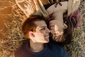 Intimate overhead shot of couple lying in golden grass.