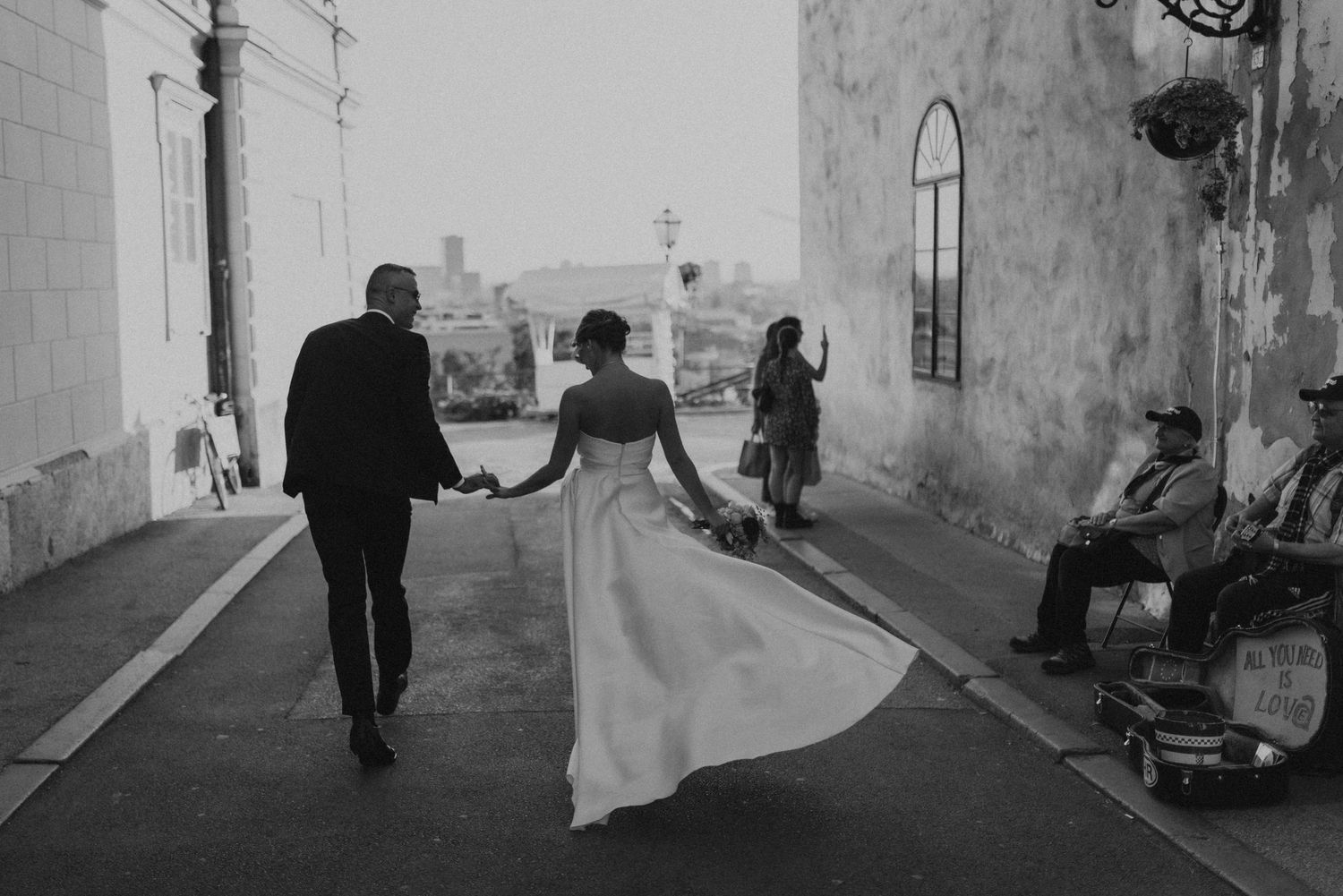 Newlyweds walking down a street together with flowing wedding dress in black and white photography.