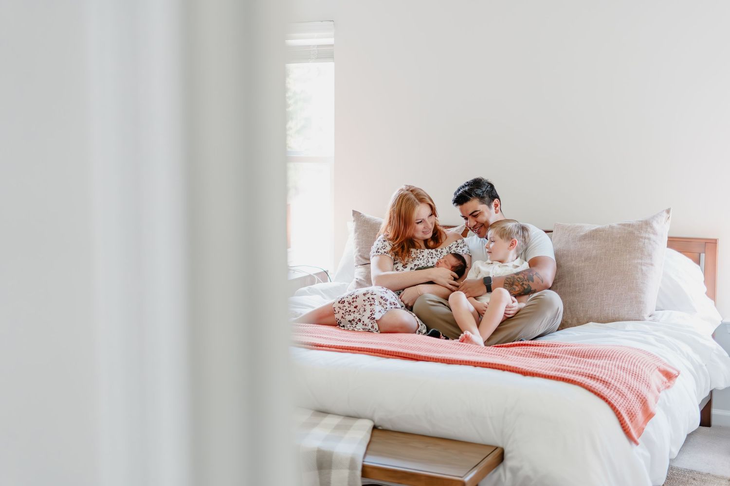 Cozy bedroom scene with soft pillows and warm pink blanket in natural light.