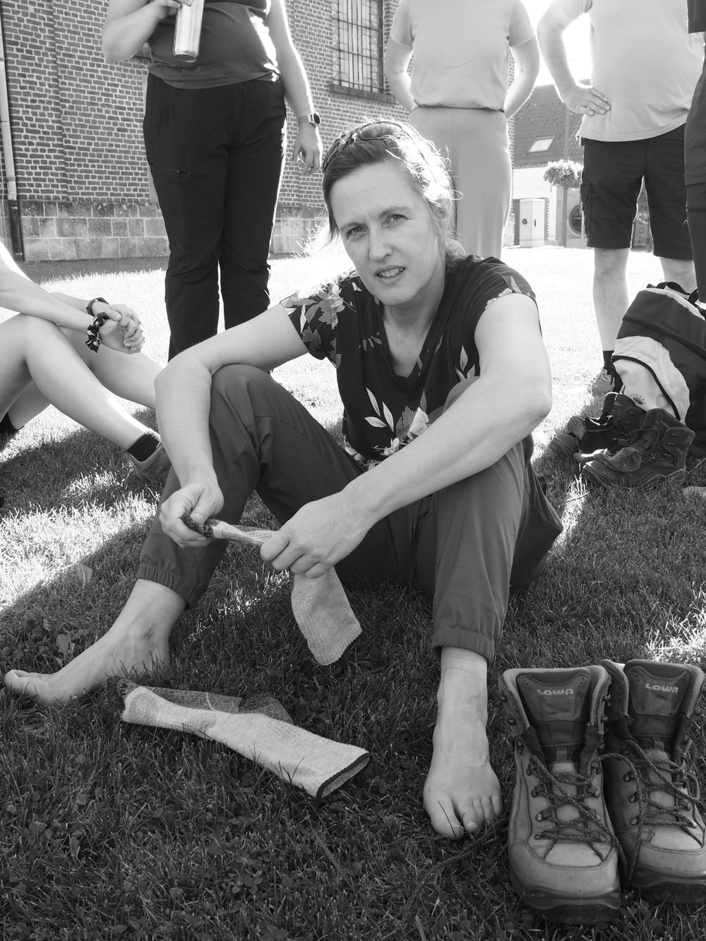 Portrait of a woman seated in the grass after taking of her hiking boots