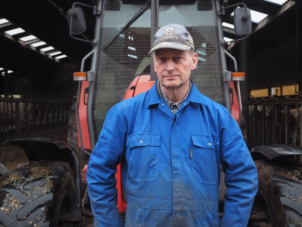 Portrait of a farmer in blue overalls in front of a red tractor