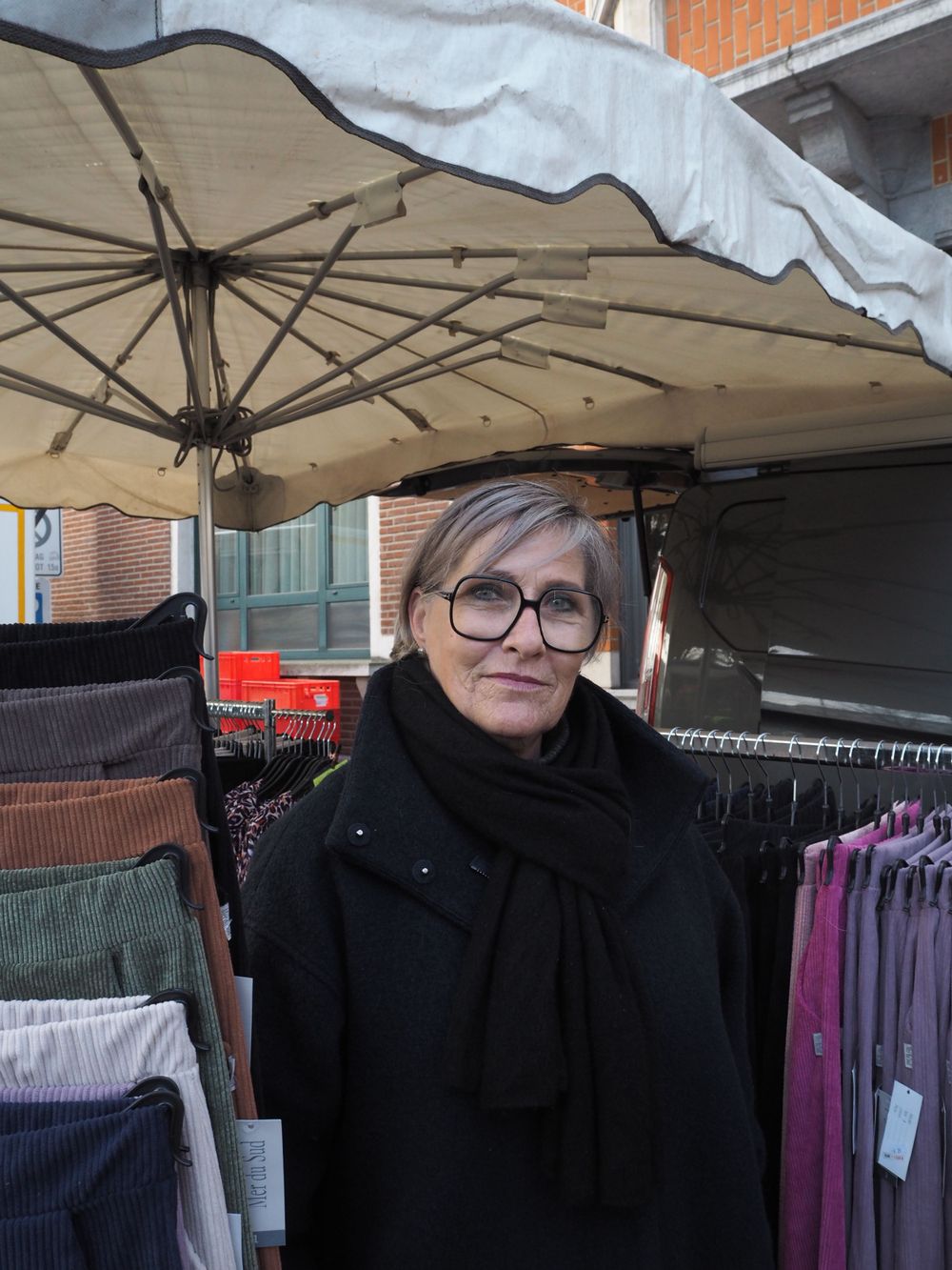 Portrait of a saleswoman with big glasses in her market stall selling clothing