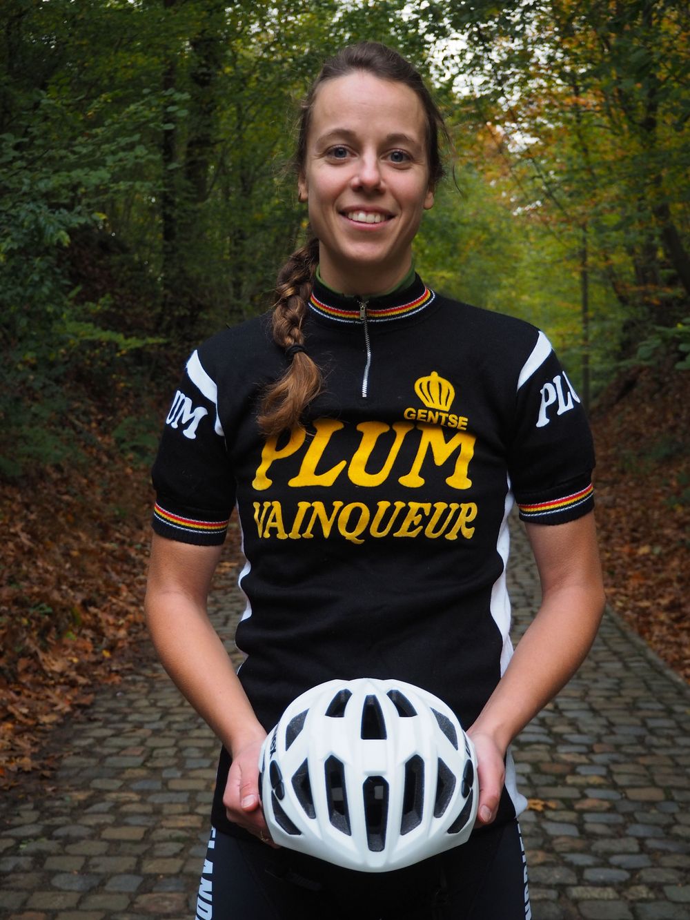 Portrait of a young woman in cycling outfit holding her white helmet