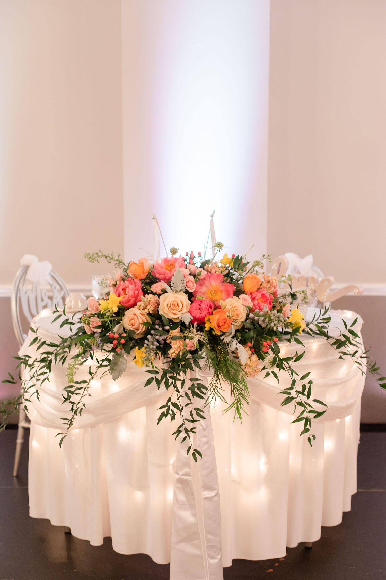 Illuminated floral display with white candles and coral flowers creating a romantic ambiance.