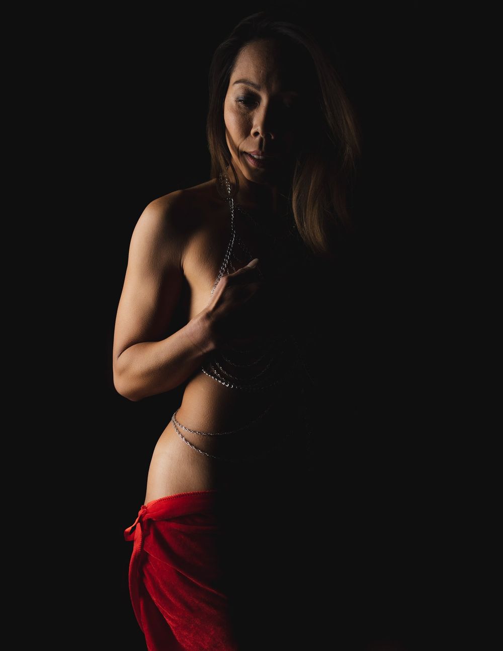 Dramatic studio portrait with subject wearing red fabric in low-key lighting.