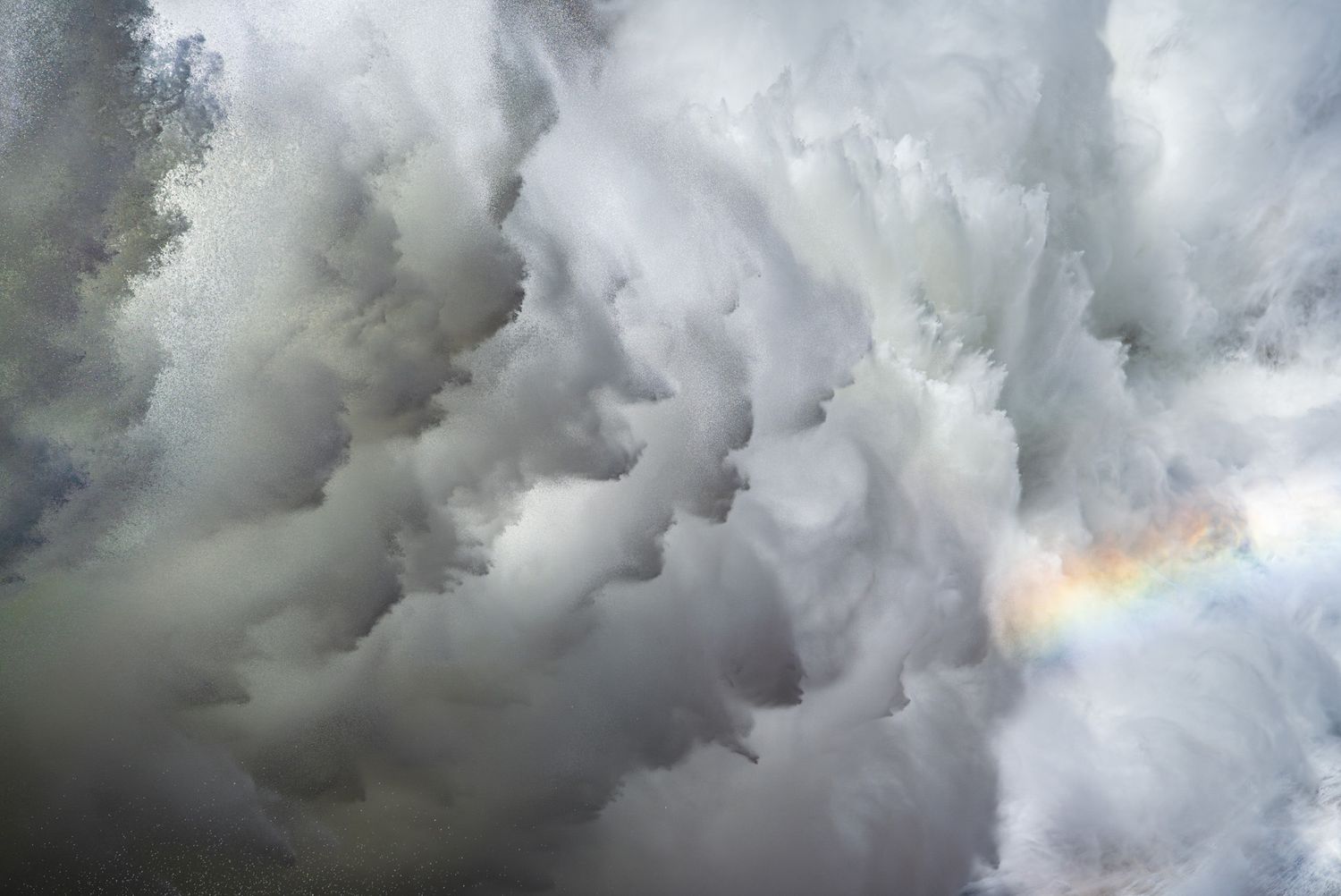 Massive waterfall spray forms cloud-like patterns with a rainbow appearing in the mist. Yosemite, California