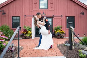 Romantic wedding photo series in front of a rustic red barn with white dress and gray suit.