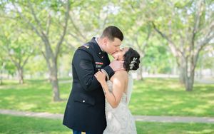 Romantic wedding couple embracing in a lush green garden setting.