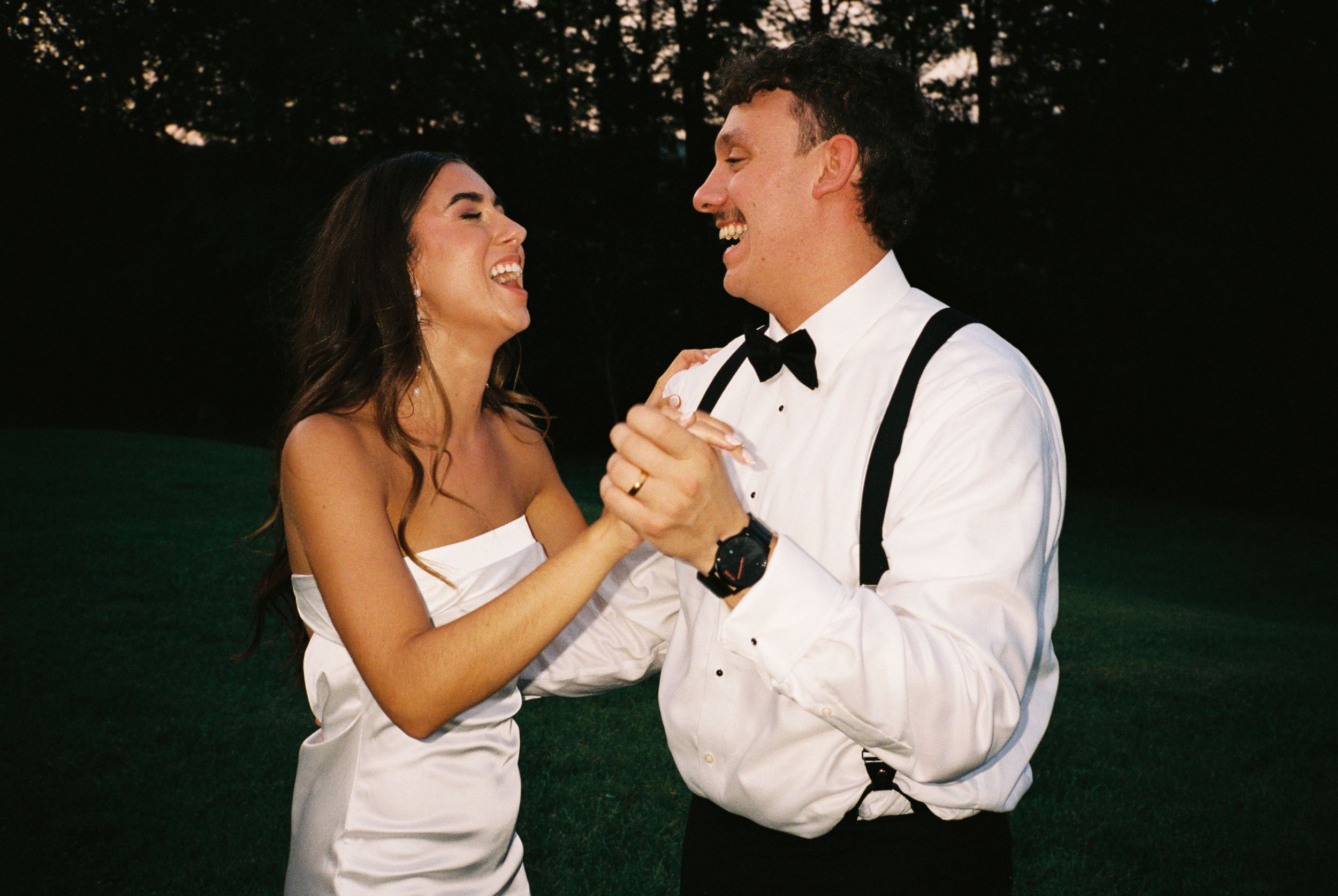 A couple laughs joyfully while dancing together at their wedding celebration.