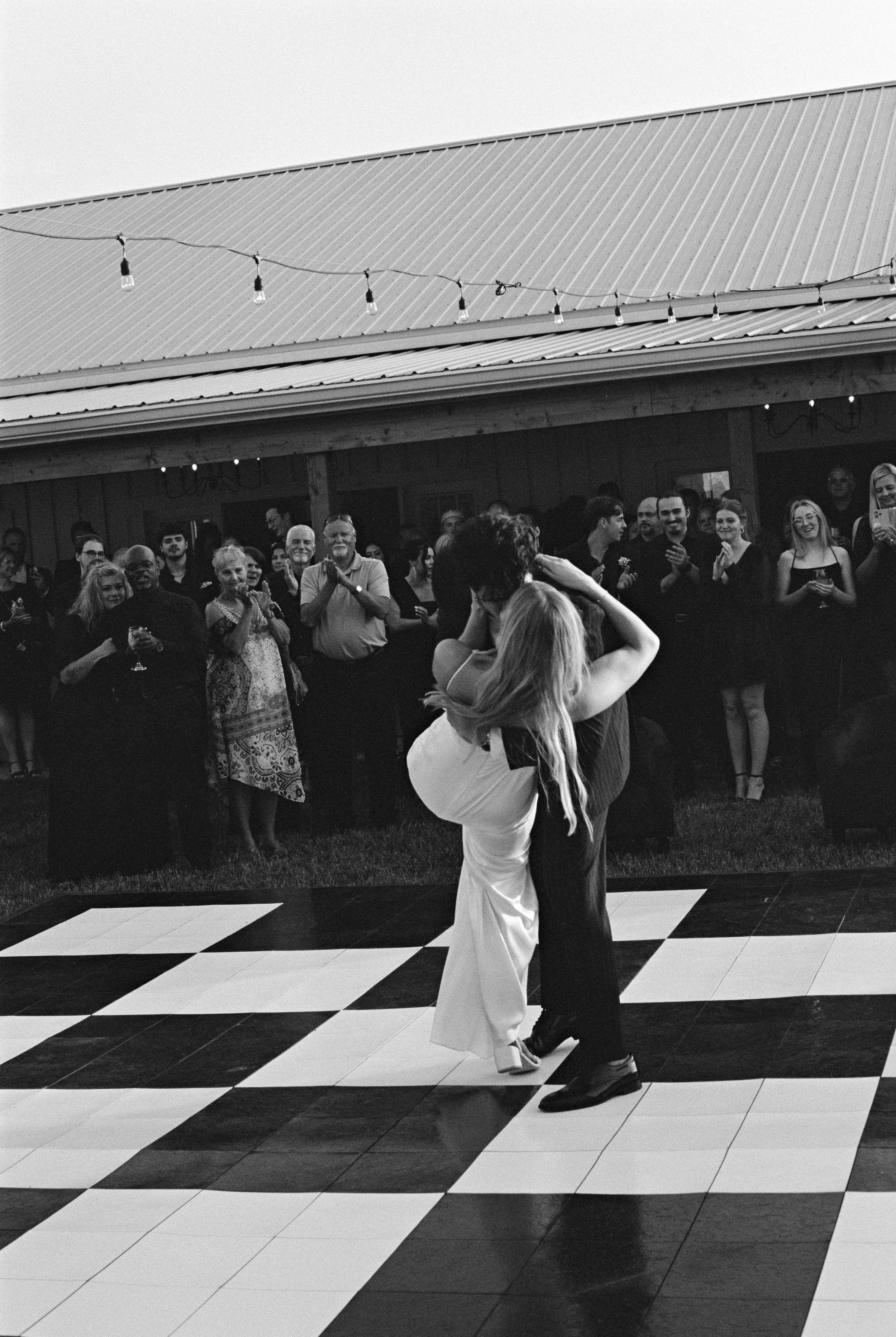 Dramatic black and white photo of wedding couple's first dance on checkerboard floor.