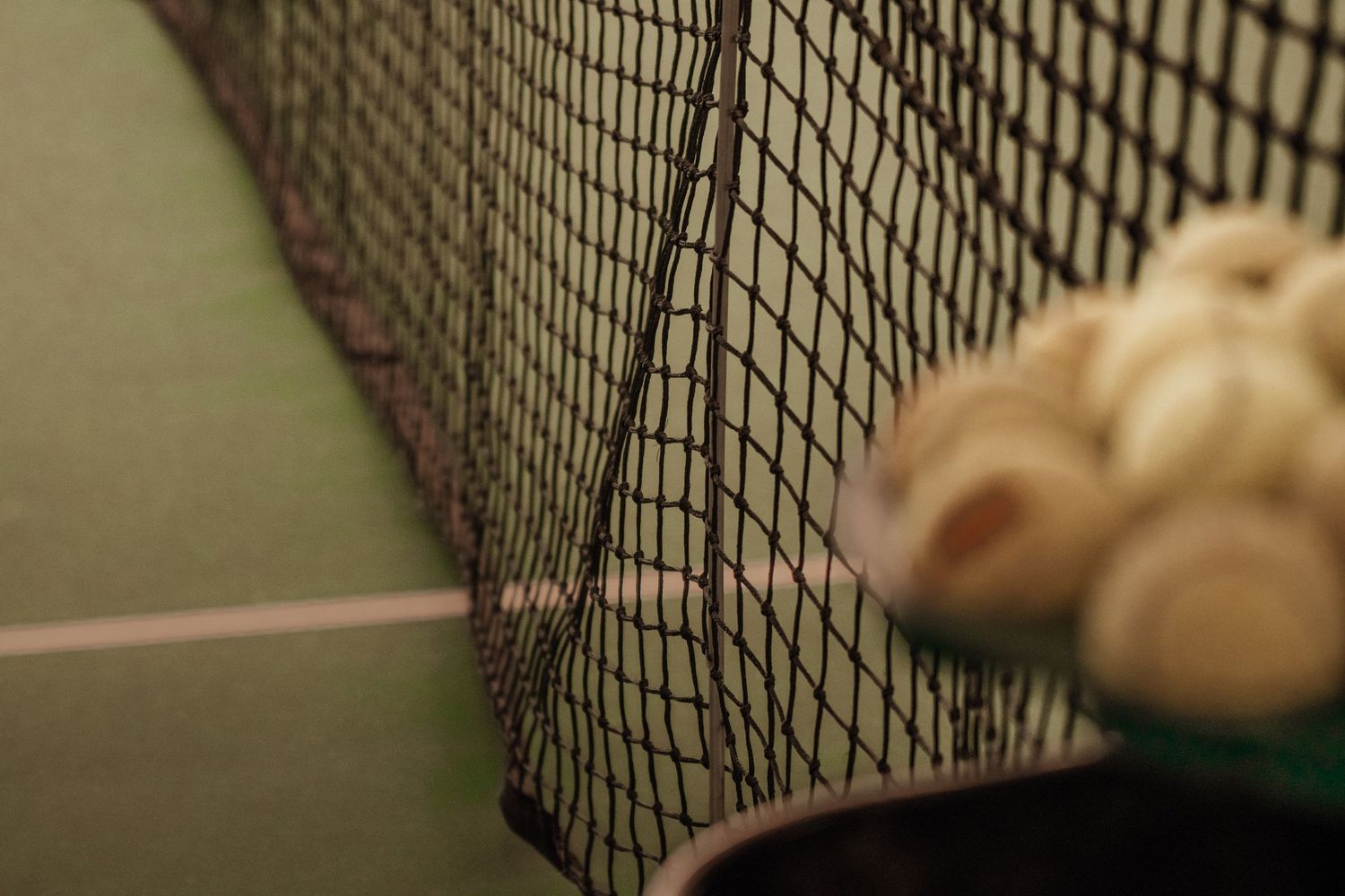 Close-up of a black tennis net with blurred background.