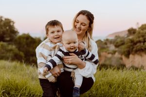 A family moment captured outdoors in a grassy field during golden hour.