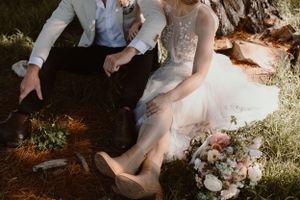 Wedding party relaxing on grass during an outdoor celebration.
