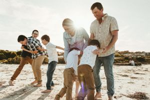 Family playing and interacting together on a sunny beach during golden hour.