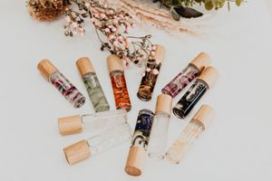 Essential oil roller bottles arranged with dried flowers on a white surface.