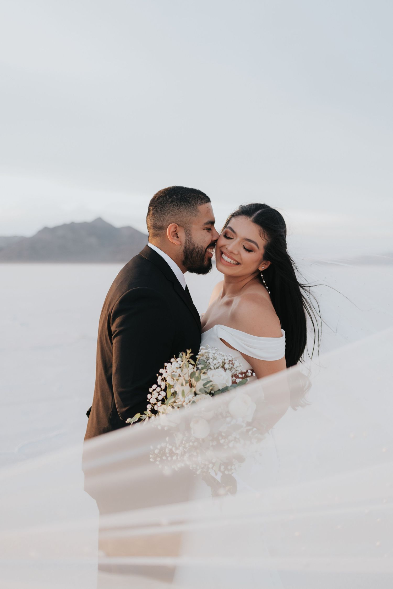 A couple smiles during their Salt Flats elopement near Salt Lake City, Utah for their destination wedding photographer