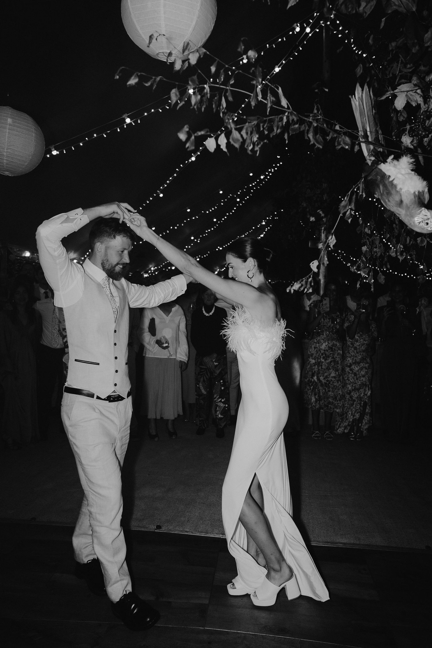 bride and groom dancing under fairy lights and lanterns during first dance in marquee in oxfordshire