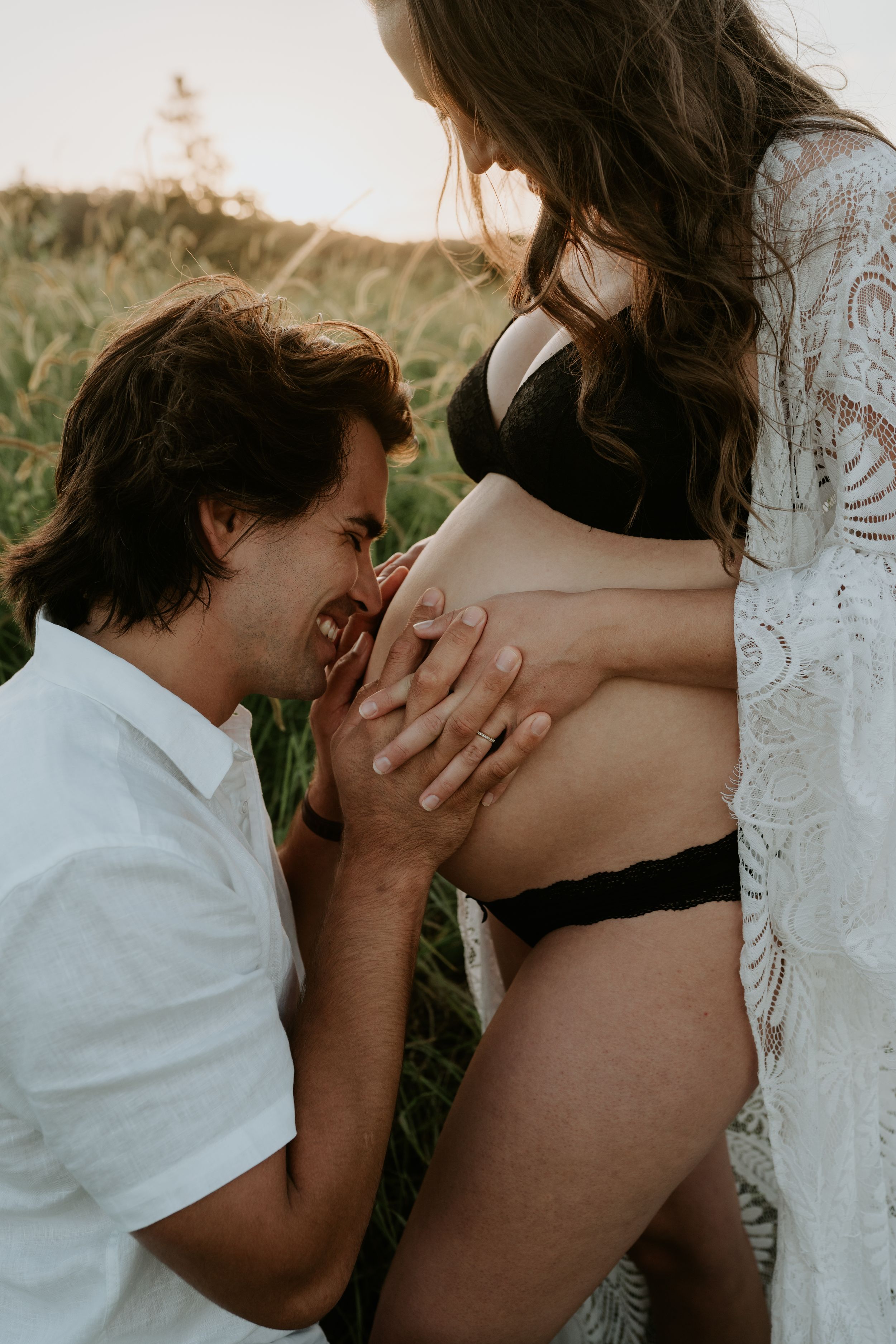 A tender maternity moment captured in a natural outdoor setting.