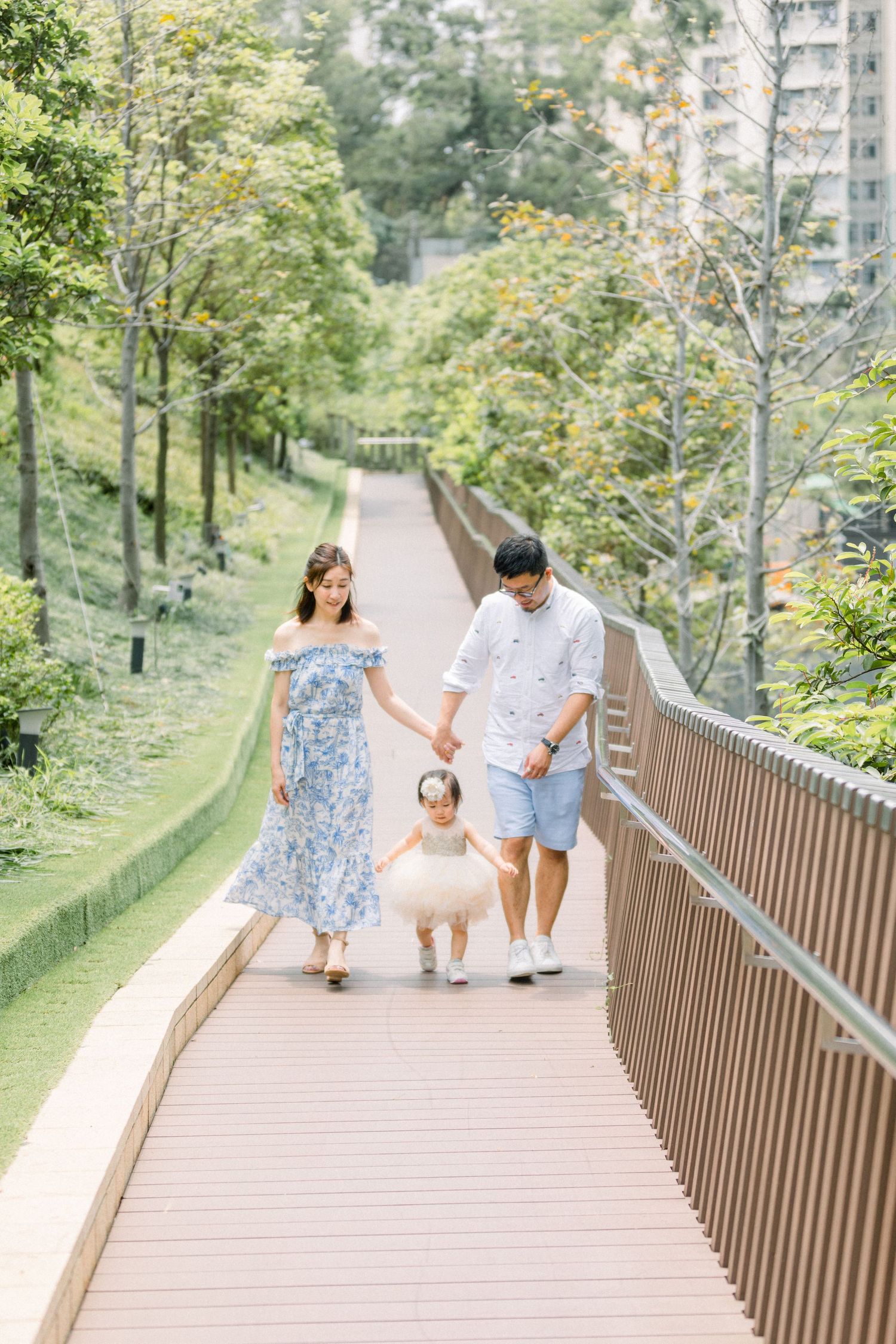 Family walking together on an elevated wooden pathway surrounded by lush greenery.