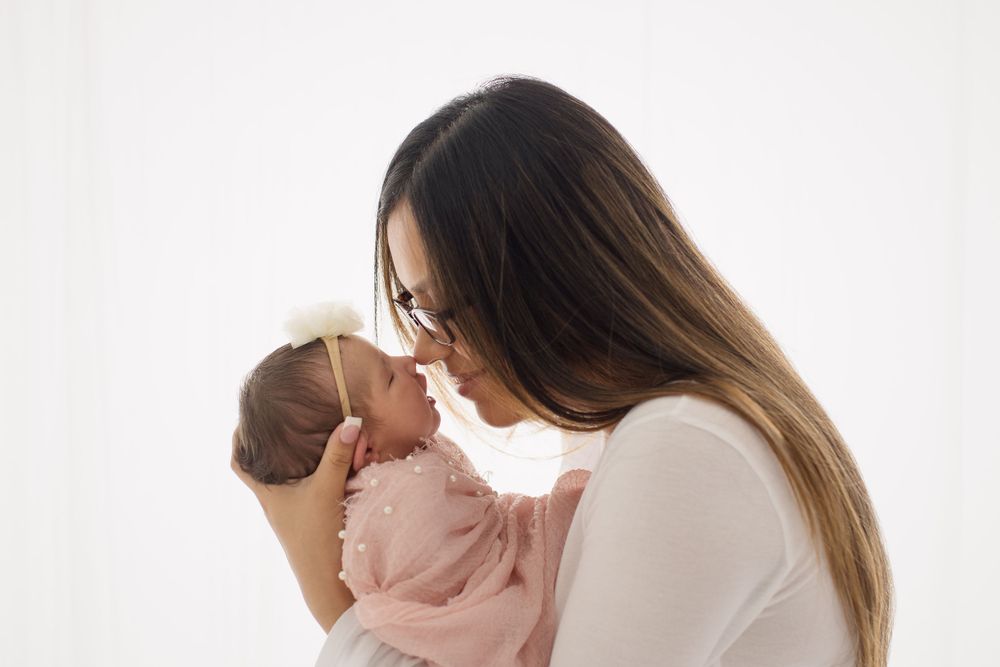 Tender moment between parent and newborn against white background.