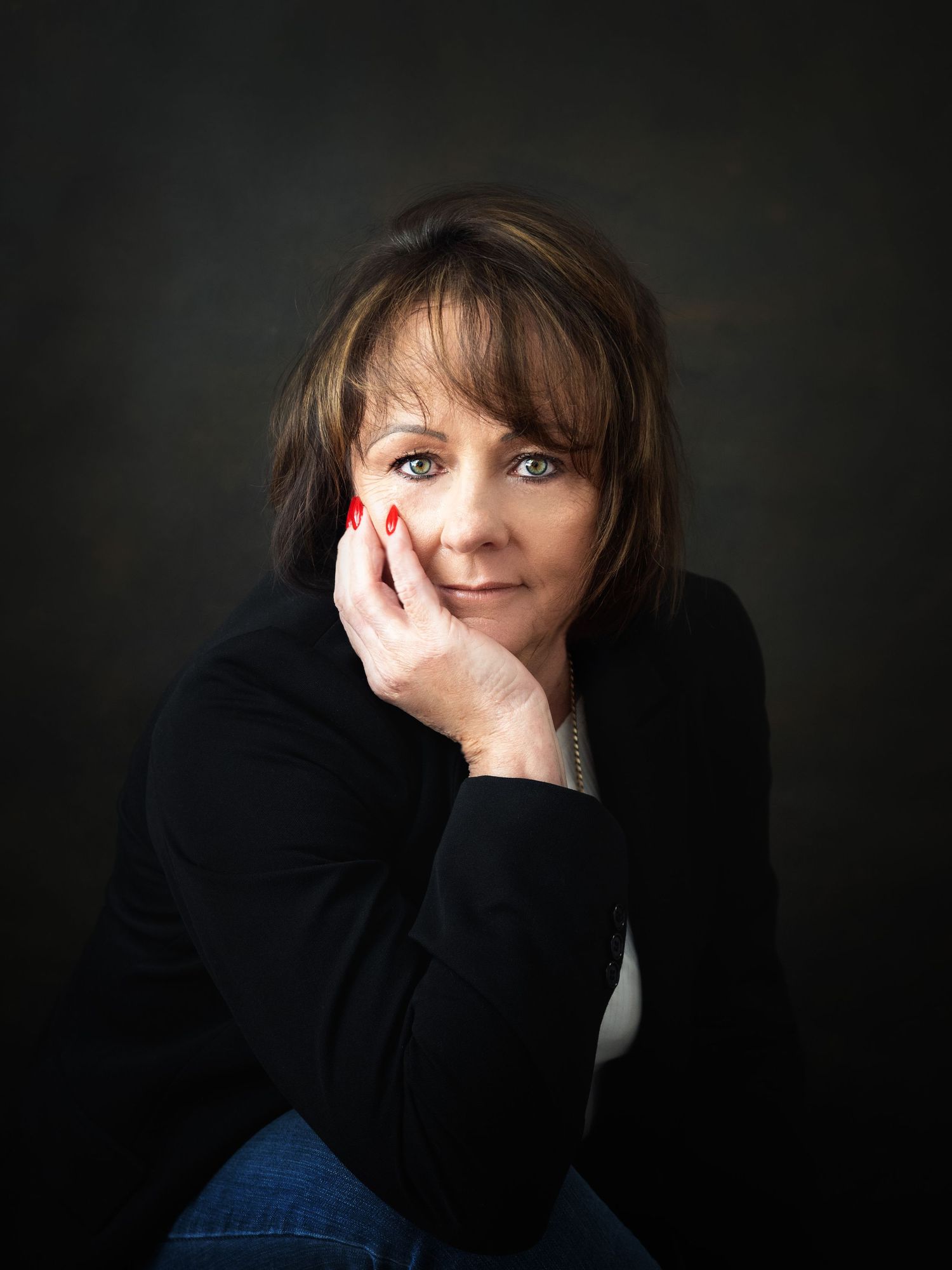 Captivating portrait of an elegant 60-year-old woman with beautiful brown hair and captivating green eyes.