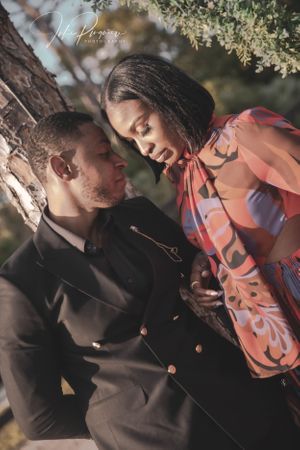 An intimate couples portrait under tree branches in warm lighting.