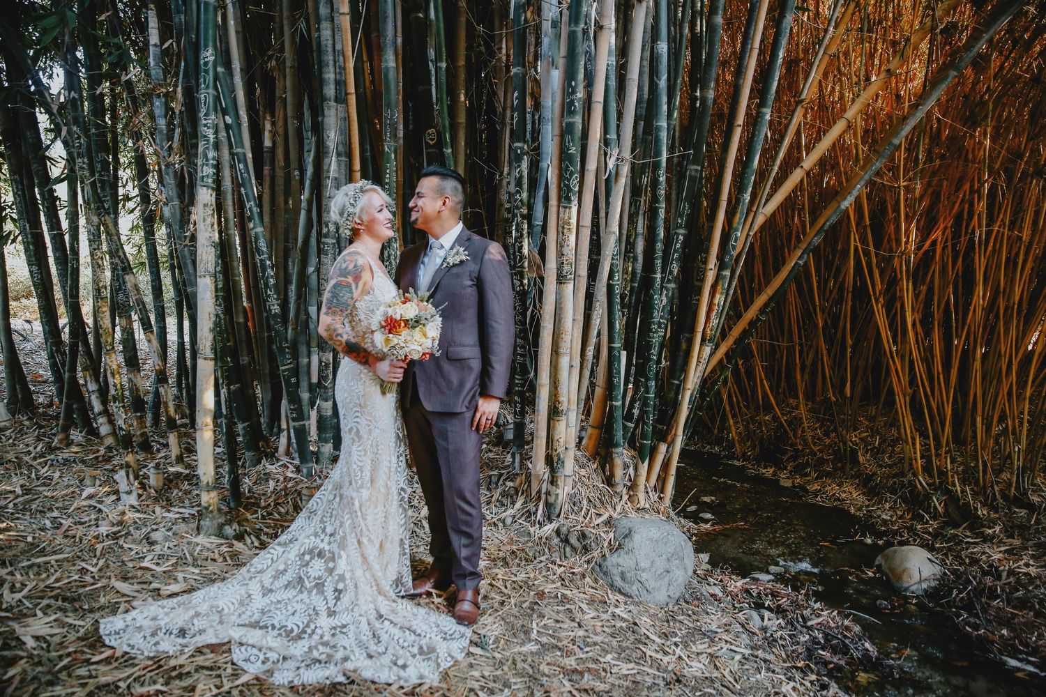 A couple stands together in a serene bamboo forest during their outdoor wedding ceremony.