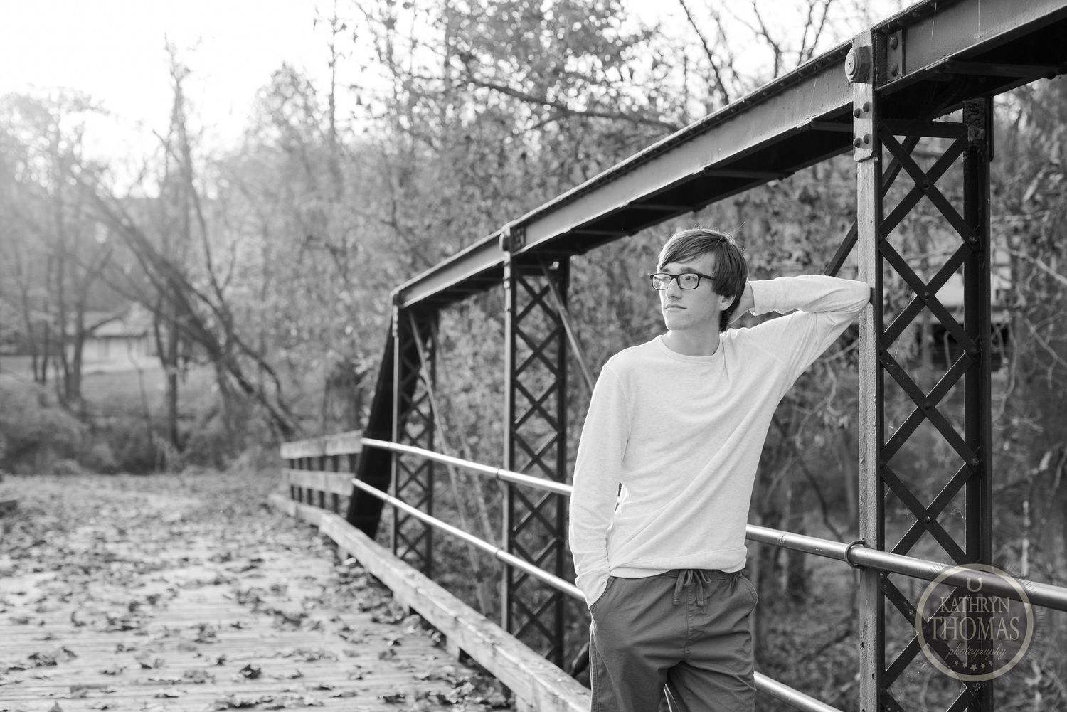 A black and white portrait of someone leaning on a bridge railing.