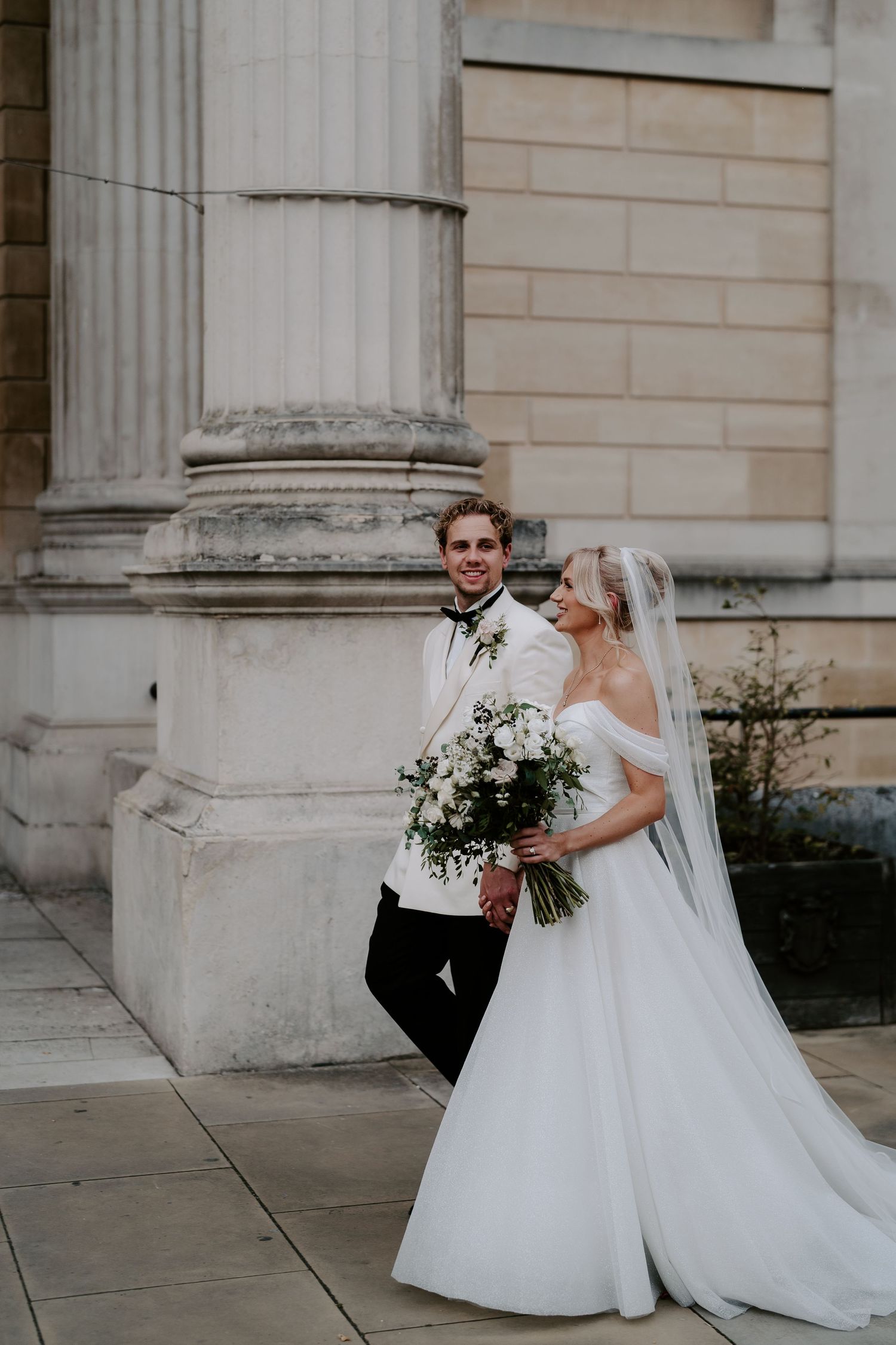 bride and groom walking outside the Ashmolean Museum in oxford