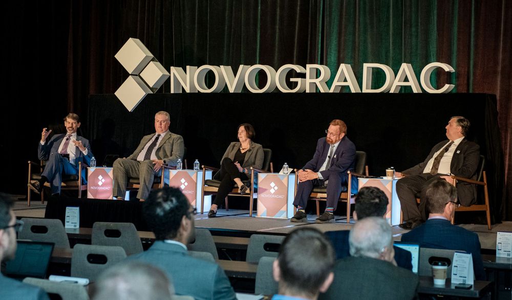 Business professionals participate in a panel discussion at a Novogradac corporate event.
