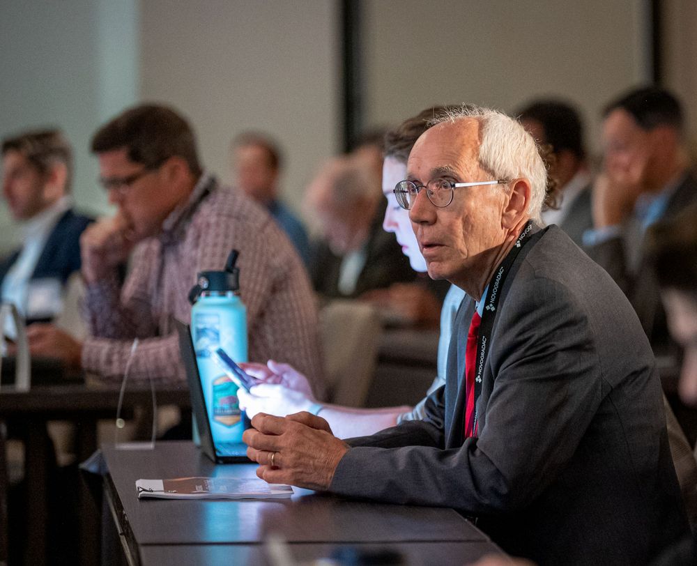 An attendee takes notes during a business conference while sitting at a table.
