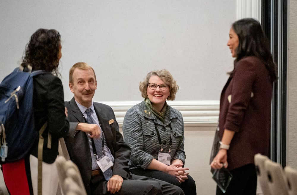 A casual networking conversation between attendees during a professional conference break.